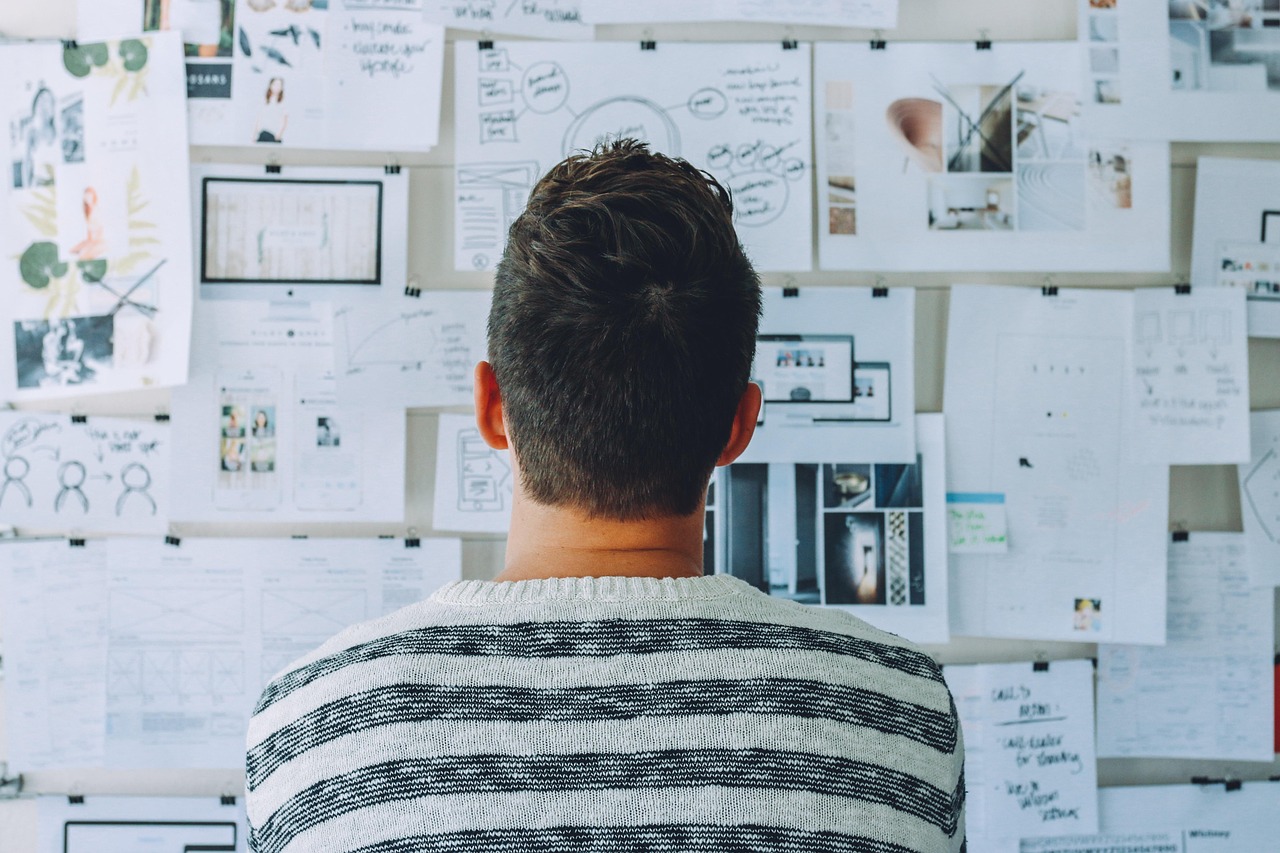 Designer reviewing a wall of printed layout concepts in the studio