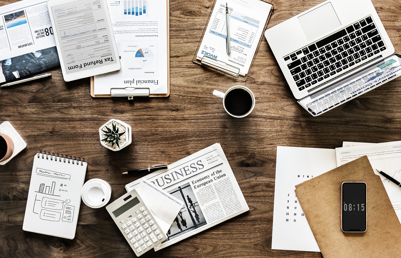 Top-down view of a marketer's desk with laptop, notebook and project plans