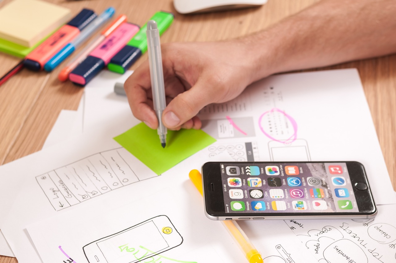 Hand sketching interface ideas beside a smartphone